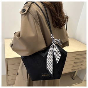 Detail of black suede tote bag with V-shaped opening and decorative checkered scarf