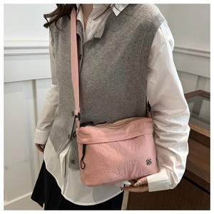 Pink nylon crossbody bag with floral logo and adjustable strap worn by a model