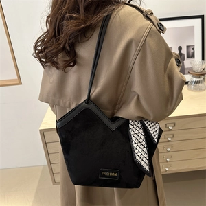 Black suede tote bag with V-shaped leather trim and plaid scarf on khaki trench coat