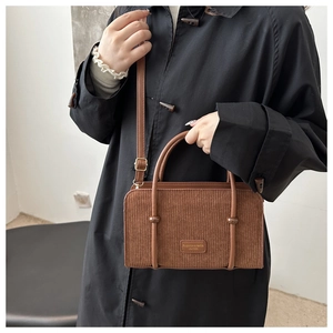 Brown corduroy handbag with leather shoulder strap worn over a black winter coat