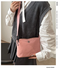 Close-up of pink nylon crossbody bag showing the round logo and adjustable strap texture
