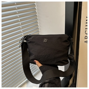 Detail of black nylon crossbody bag with clover metal buckle and wide knit strap
