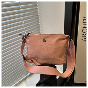 Pink nylon crossbody bag detail with black clover logo and adjustable wide strap