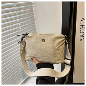 Detailed close-up of nylon crossbody bag with floral logo and wide woven strap