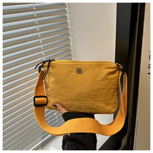 Detail of yellow nylon crossbody bag with black flower logo and textured fabric