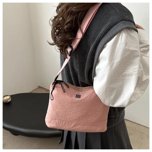 Detail view of pink nylon crossbody bag featuring adjustable strap and black metal logo