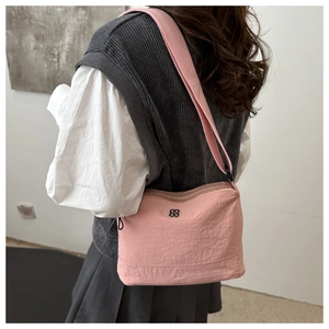Side view of a pink nylon crossbody bag with black logo and wide shoulder strap
