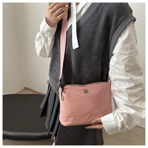 Detailed view of pink nylon crossbody bag with silver logo and adjustable wide fabric strap