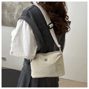 Detail view of cream nylon crossbody bag with adjustable strap worn by model