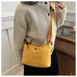 Detail of yellow nylon crossbody bag featuring black flower logo and adjustable strap