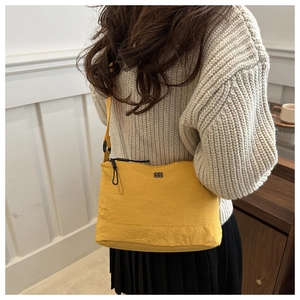 Detail of ginger yellow nylon crossbody bag featuring textured fabric and logo