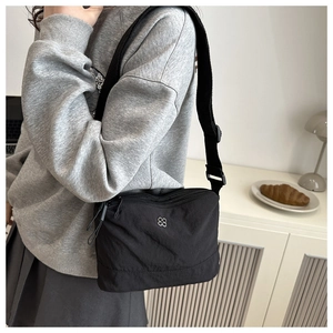 Detail of black sporty crossbody bag with clover logo and adjustable wide strap