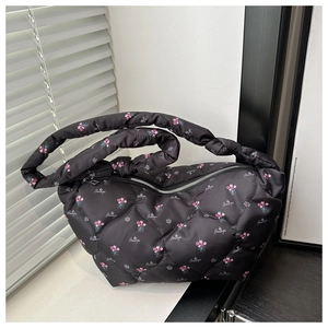 Detail of black quilted dumpling bag with pink floral prints and Beautiful lettering text