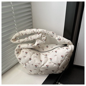 Close-up of white quilted dumpling bag with floral prints and 'Beautiful' text