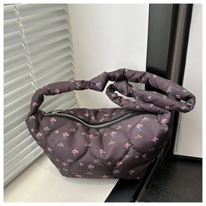 Detail of dark floral quilted puffer bag showing glossy nylon fabric and zipper