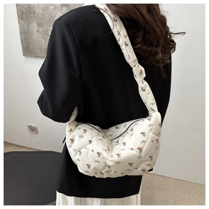 Detail of white quilted dumpling bag with floral prints and embroidery on model