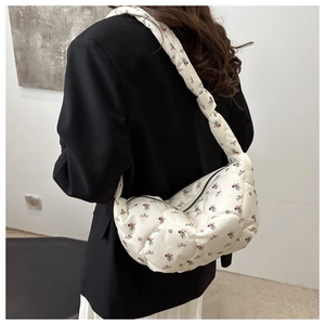 Détail du sac bandoulière blanc matelassé avec motifs floraux et écriture artistique