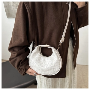 Détail du sac demi-lune blanc tressé avec texture géométrique et boucles dorées