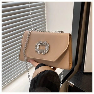 Detail of elegant beige crossbody bag with sparkling rhinestone buckle and silver chain