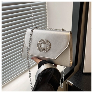Detail of silver crossbody bag with crystal buckle and metallic chain strap