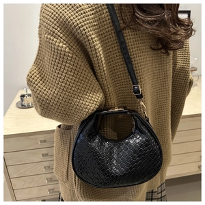 Detail of black woven texture on crescent bag with elegant gold buckle and hardware
