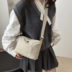 Beige casual nylon crossbody bag with wide shoulder strap and floral logo shown on model