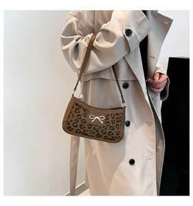 Side view of leopard print shoulder bag with bow detail on a beige trench coat