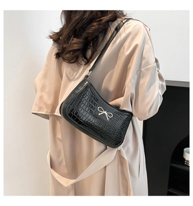 Elegant black crocodile-pattern shoulder bag featuring a decorative gold bow charm