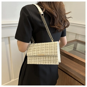 Detailed view of white tweed shoulder bag with gold chain strap and metallic clasp closure