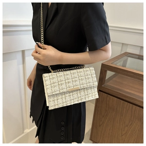 Detailed close-up of tweed small square bag with elegant gold chain and metal buckle
