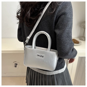 Silver metallic leather mini bucket bag with logo shown in a minimalist lifestyle setting