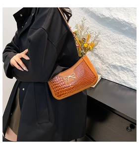 Detail of retro orange crocodile pattern handbag with a golden metal bow decoration