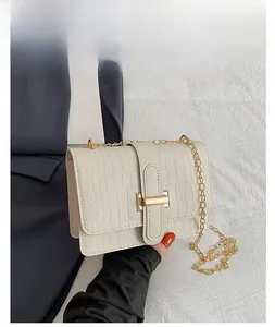Close-up of white croc-effect crossbody bag with gold H-clasp and chain strap