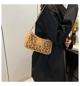 Detail of leopard print underarm bag featuring a golden bow metal buckle on black coat