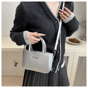 Silver metallic leather crossbody bag with dual handles and metal logo detail