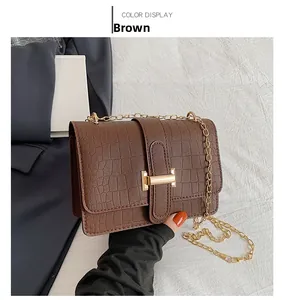 Detail of brown crocodile pattern shoulder bag with gold chain and metal buckle