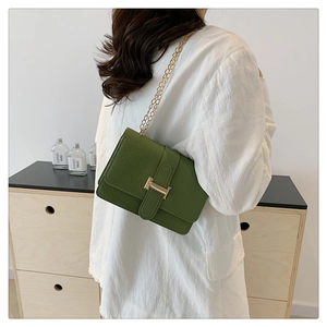 Detail of green crocodile texture shoulder bag with gold H-buckle worn by a model