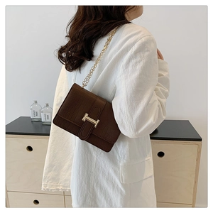 Brown crocodile pattern crossbody bag with gold chain strap shown on a model