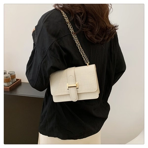 Detail of off-white crocodile embossed crossbody bag with gold chain and metal buckle