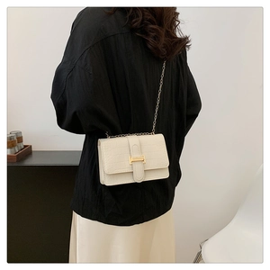 Close-up of cream crocodile pattern leather bag with golden chain and metal buckle