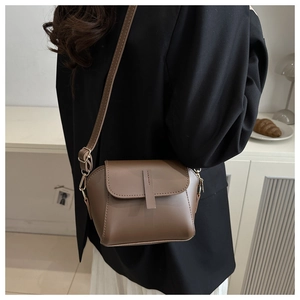 Mocha brown leather crossbody bag detail on model in a minimalist room setting