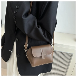 Detailed view of brown matte leather crossbody bag with adjustable strap and gold hardware