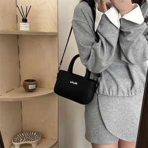Secchiello minimalista in pelle nera con logo elegante su scaffale di legno