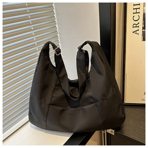 Detail of black nylon hobo tote bag with adjustable strap and silver metal buckle