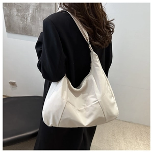 Detail of a large cream nylon tote bag with textured finish shown on shoulder
