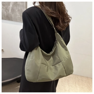 Rear view of a grass green padded nylon tote bag worn over the shoulder by a woman