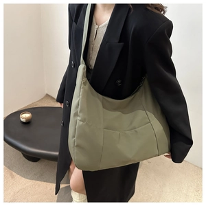 Detail of spacious nylon tote bag in olive green worn as a shoulder bag for commute