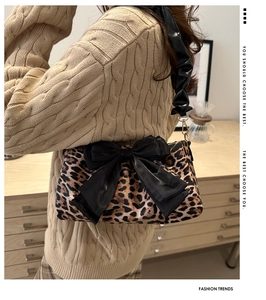 Detail of leopard print handbag with oversized black bow and ruffled shoulder strap