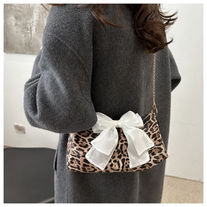 Dettaglio borsa baguette leopardata con fiocco in tulle bianco e tracolla a catena oro