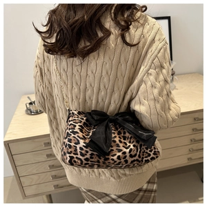 Dettaglio borsa leopardata con grande fiocco nero e sottile tracolla a catena dorata